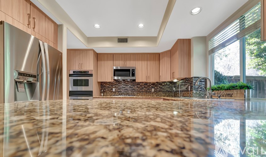 A kitchen with wooden cabinets and a marble countertop.