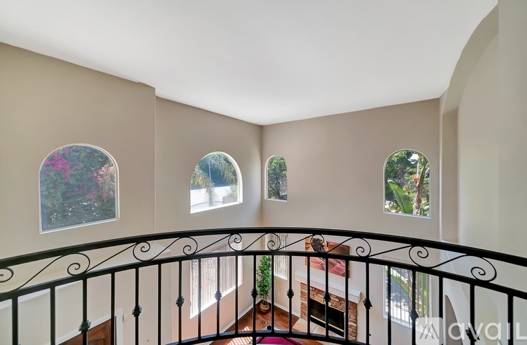 A staircase with a black railing leads to a landing with three windows.
