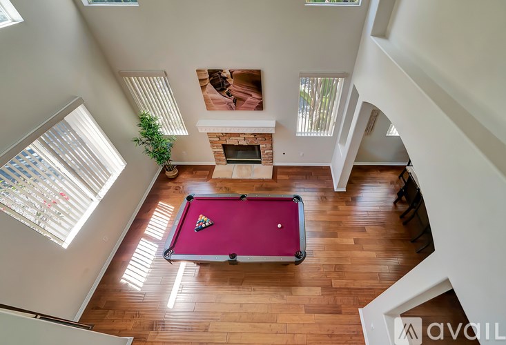 A pool table in a room with wooden floors and a fireplace.