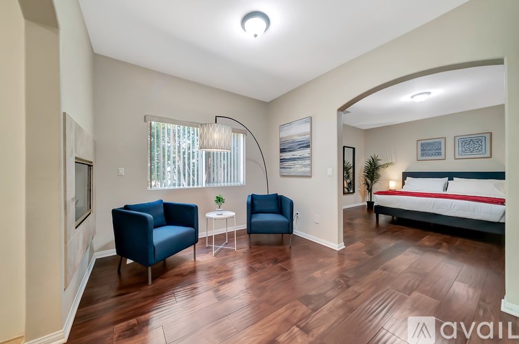 A bedroom with a bed, two chairs, and a table.