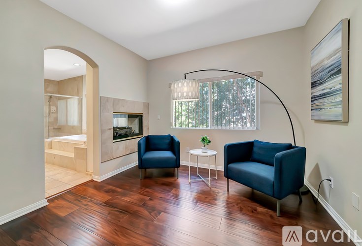 A living room with a blue chair and a small table with a plant on it.