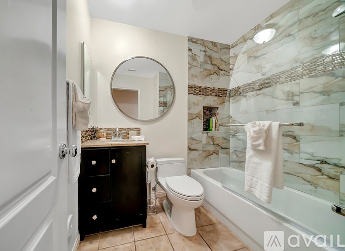 A bathroom with a marble wall and a round mirror above a vanity.