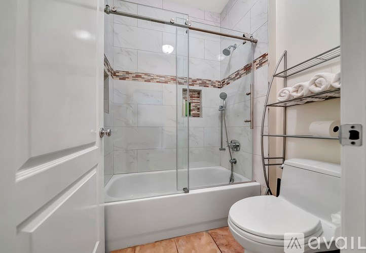 A white bathroom with a glass shower enclosure and a toilet.