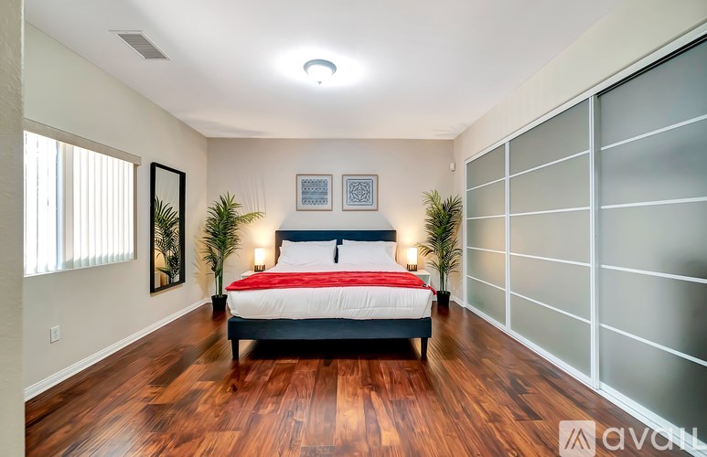 A bedroom with a bed, two lamps, and a plant.