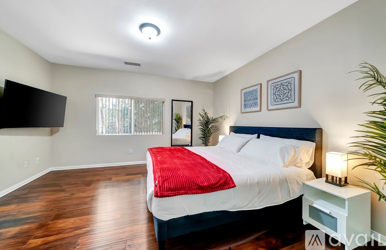 A bedroom with a bed, nightstand, and a television mounted on the wall.