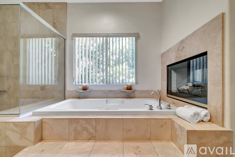 A bathroom with a large tub and a window with blinds.