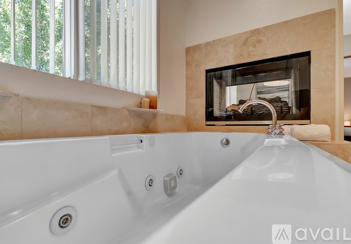 A white bathtub with a faucet and a window with blinds.