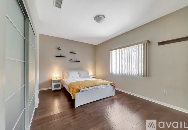 A bedroom with a bed, nightstands, and a window with blinds.