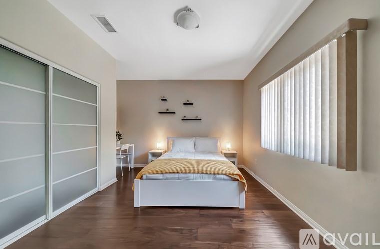 A bedroom with a bed, nightstands, and a window with blinds.