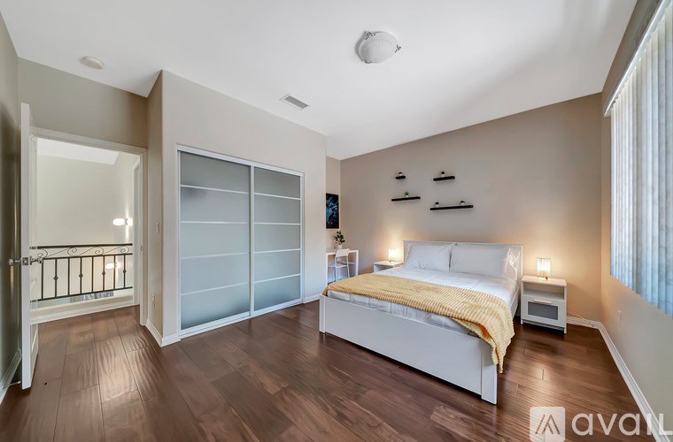 A bedroom with a bed, nightstand, and a window with blinds.