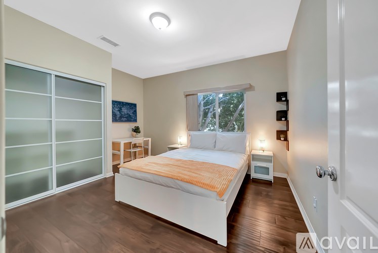 A bedroom with a bed, nightstand, and window.