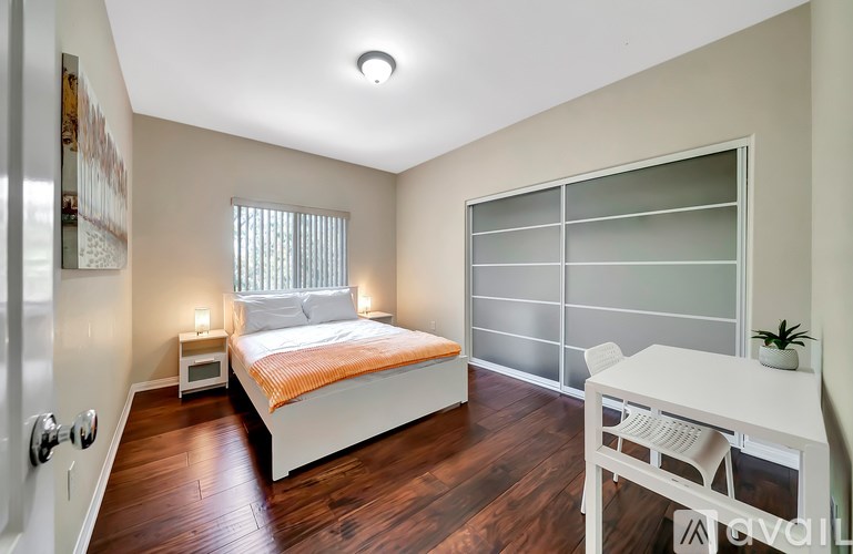 A bedroom with a bed, desk, and window.