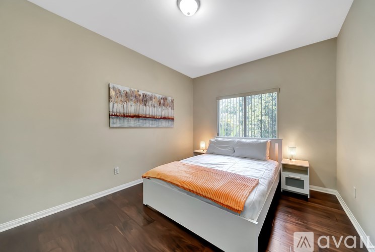 A bedroom with a white bed and a painting on the wall.