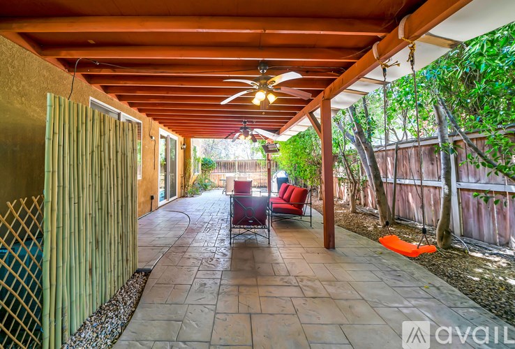 A patio with a red chair and a ceiling fan.