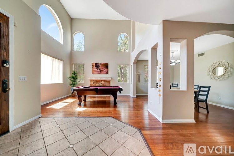 A living room with a wooden floor and a large rug in the center.
