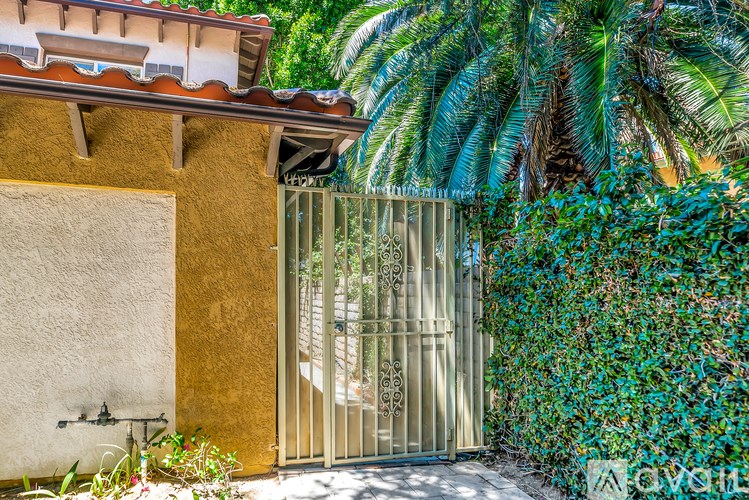 A house with a brown wall and a gate with a metal design.