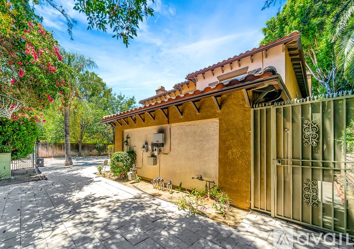 A house with a red tile roof and a green gate.