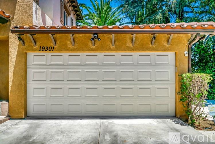 A white garage door with the number 19301 on the wall above it.