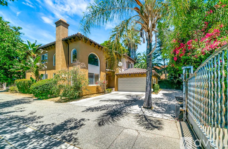 A house with a driveway and a palm tree in front.