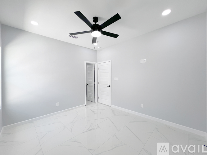A room with a ceiling fan and a door.