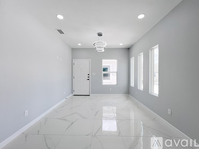 A spacious room with marble flooring and a white door.