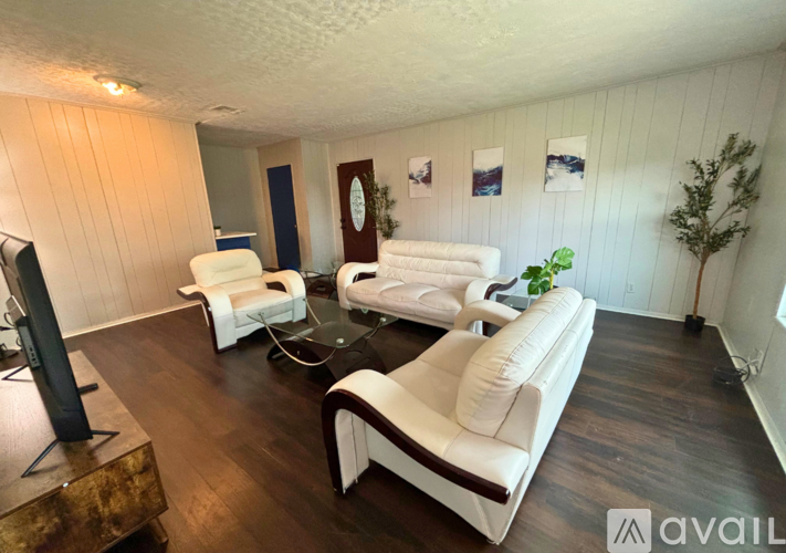 A living room with white furniture and a wooden floor.