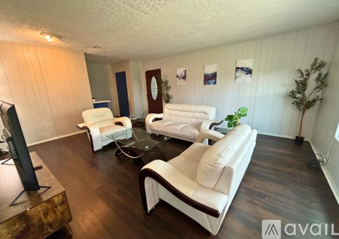 A living room with white furniture and a wooden floor.