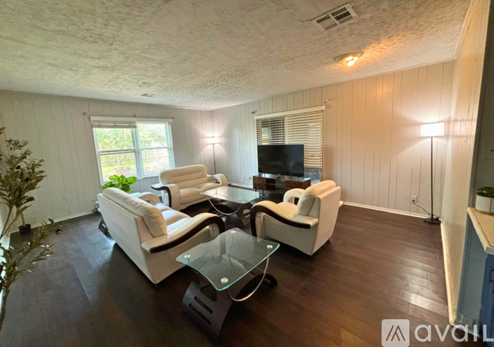 A living room with a white couch and a glass coffee table.