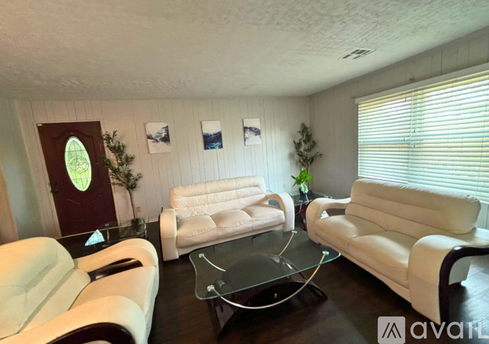 A living room with white leather furniture and a glass coffee table.