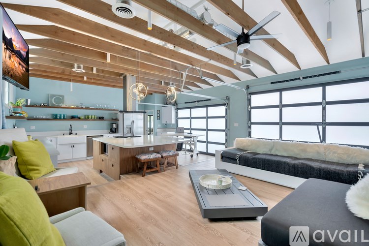 A modern kitchen with a large island and a bed in the background.