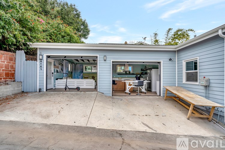 A garage with a white car inside and a wooden bench outside.