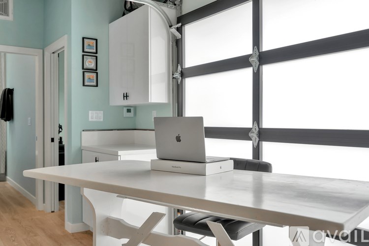 A laptop is on a table in a room with a white cabinet and a window.