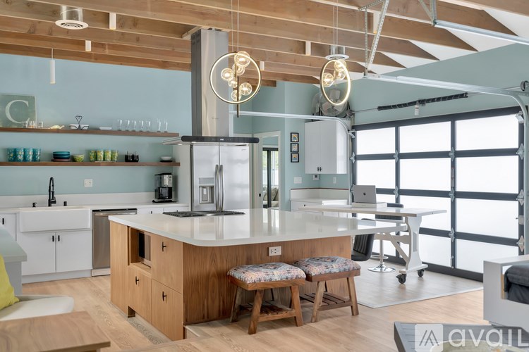 A modern kitchen with a large island and wooden stools.