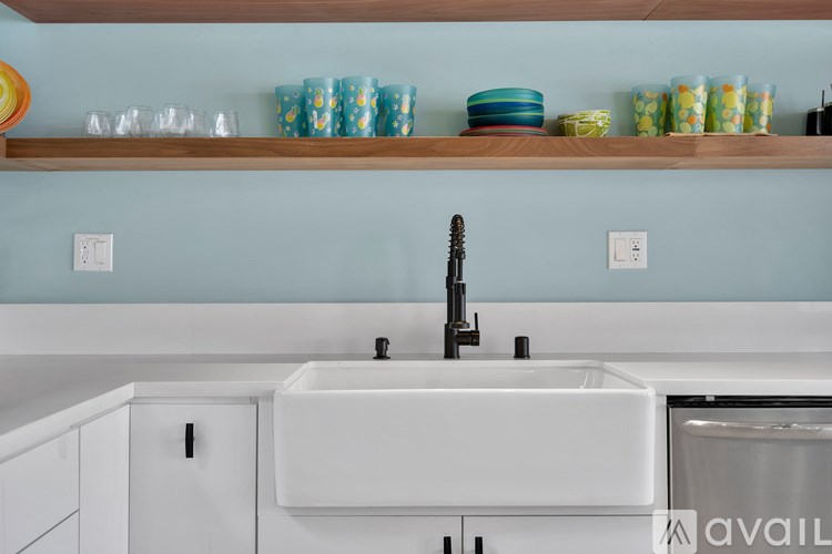 A kitchen with a white sink and a wooden shelf above it.