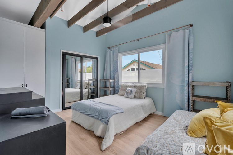 A bedroom with a bed, a bedside table, and a window with curtains.