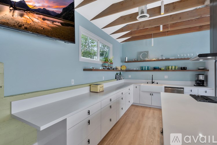 A modern kitchen with a large island and a flat screen TV mounted on the wall.