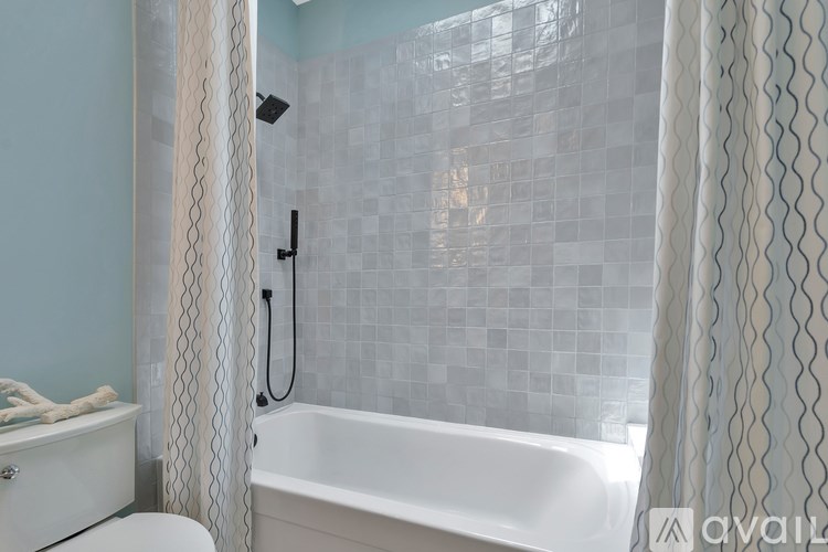 A white bathtub sits next to a shower curtain in a bathroom.