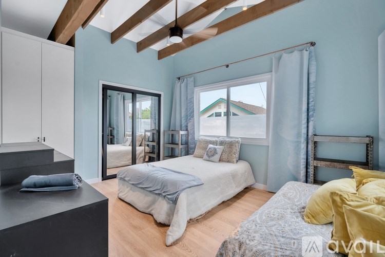 A bedroom with a bed, a dresser, and a window with curtains.