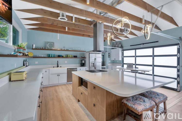 A kitchen with wooden floors and a large island with a stool.