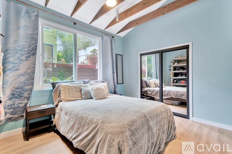 A bedroom with a bed, a window with curtains, and a wall mural.