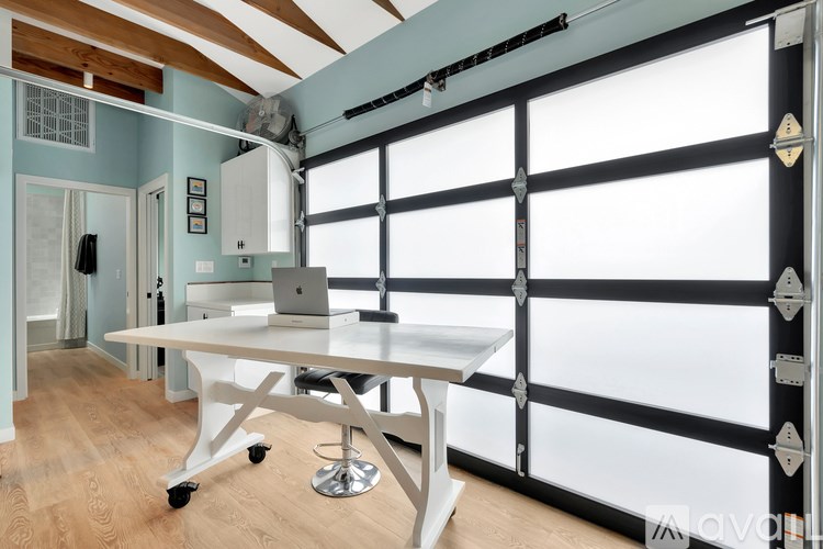 A white desk with a laptop on it in a room with a large window.