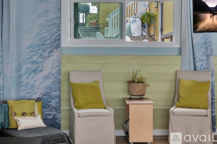Two chairs with yellow pillows are in front of a green wall.