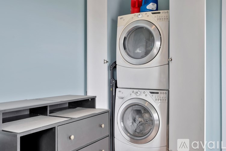 A stack of two washing machines in front of a wall.