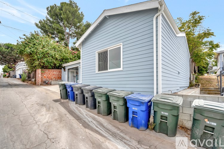 A blue house with a row of bins in front.