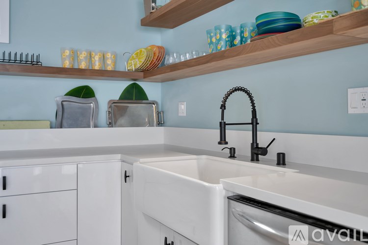 A kitchen with a white sink and a wooden shelf above it.