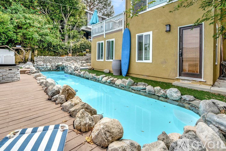 A pool surrounded by rocks and a striped mat.