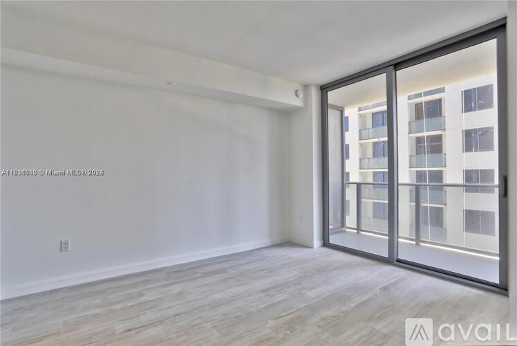 A spacious room with a sliding glass door leading to a balcony.