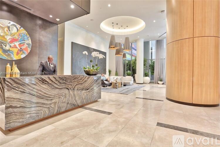 A reception area with a marble counter and a man standing behind it.