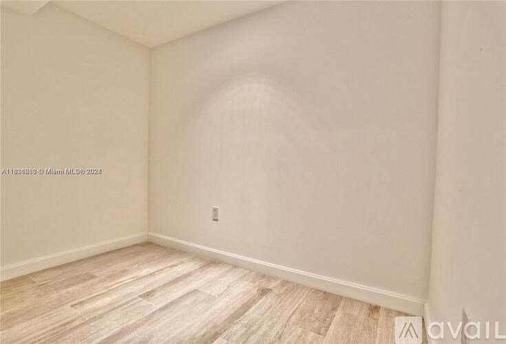 A room with wooden flooring and a light switch on the wall.