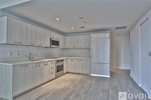 A modern kitchen with white cabinets and a wooden floor.